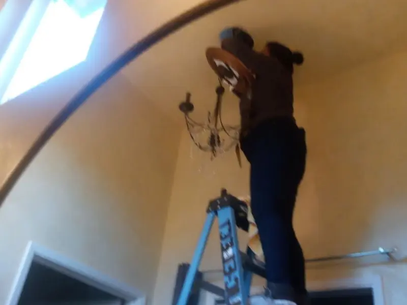 Electrician installing a chandelier in a Alabaster residence